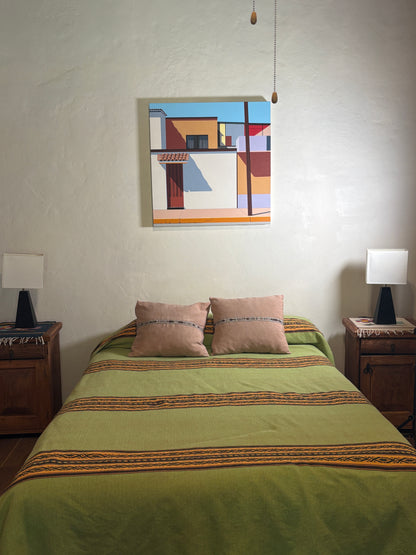 Bedroom with green bedspread, abstract painting on wall, and wooden nightstands.